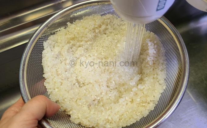 米をザルに入れて洗っている写真